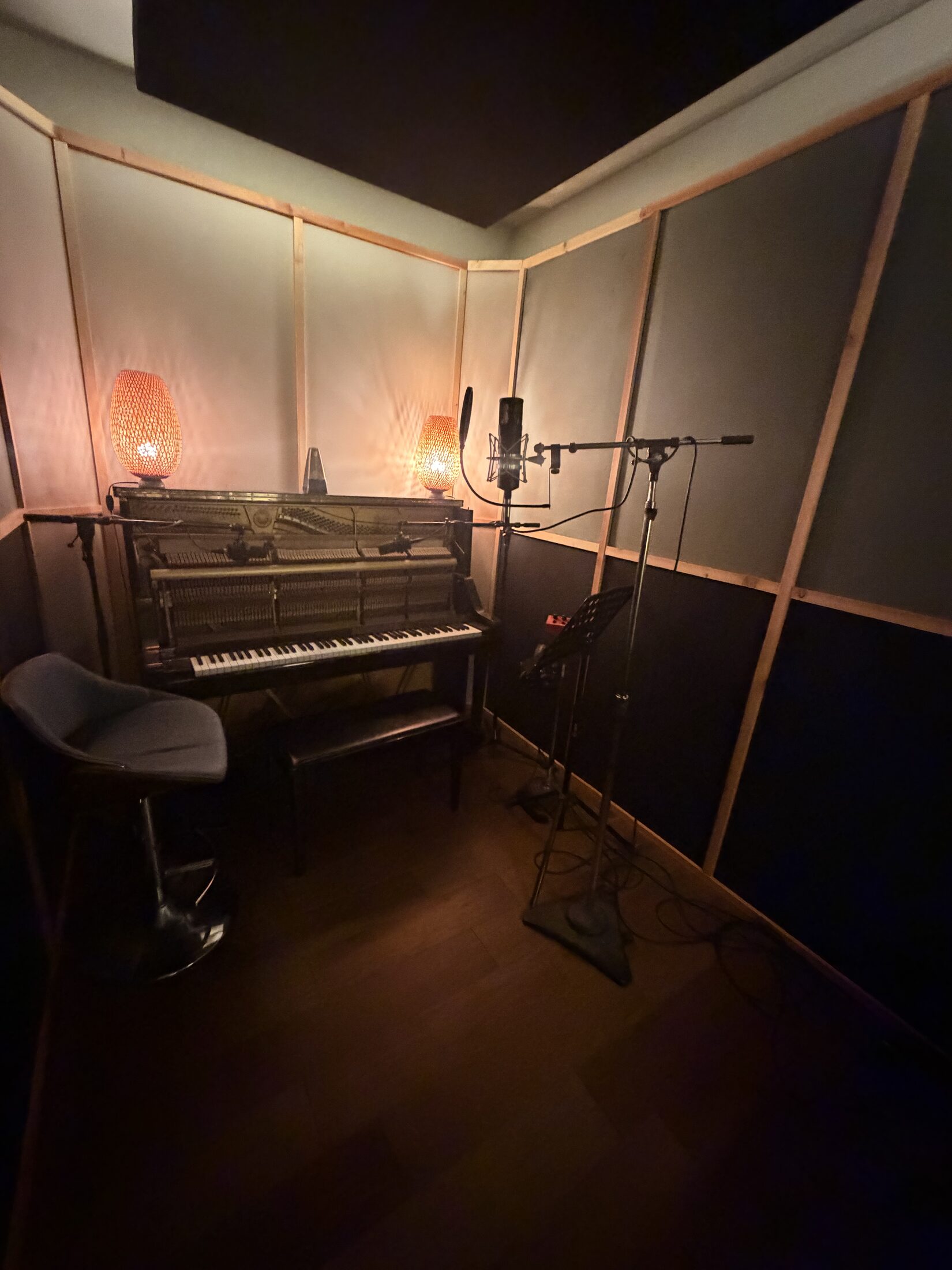 Isolated vocal booth with upright piano and ribbon microphone